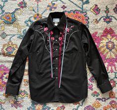 ☆ Description -Tag Rockmount Ranchwear shirt -Black 50% polyester 50% cotton with pink floral embroidery -Western piping detail front and back -Attached neck ribbons -Pearl snap buttons ~Made in USA~ ☆ Measurements  Measurements (taken flat) - fits like Ladies M Shoulders (seam to seam) : 17" Bust (flat x 2) : 44" Waist (flat x 2) : 40" Hips (flat x 2) : - Length : 25" Sleeve Length : 24" Tag : Rockmount Ranch Wear / 38 ☆ Material Cotton polyester blend ☆ Seller Note All items are sold as is. Pl Ascot Ties, Western Pearl Snap, Ranch Wear, Lady M, Tie Shirt, Floral Embroidery, Pink Floral, Black Shirt, Favorite Outfit