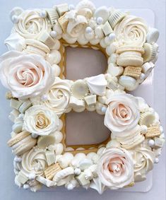 the letter b made out of seashells and roses is decorated with icing