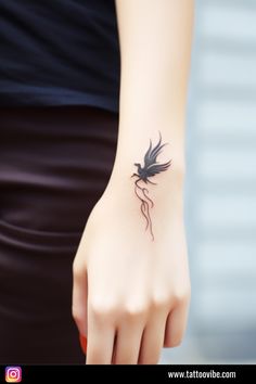 a woman's hand with a small black dragon tattoo on her left arm and wrist