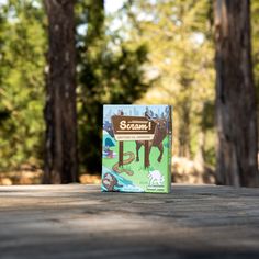 a book sitting on top of a wooden table in front of some trees and grass