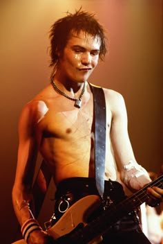 black and white photograph of a shirtless man playing an electric guitar