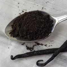 a spoon filled with dirt next to an vanilla stick