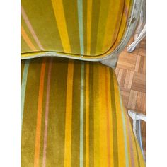 an upholstered chair with yellow, green and orange striped fabric on the back