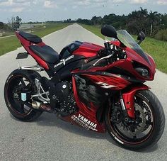 a red and black motorcycle parked on the side of a road