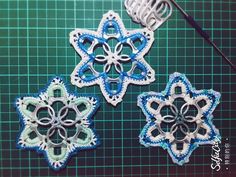 three crocheted snowflakes sitting on top of a green table next to a wire