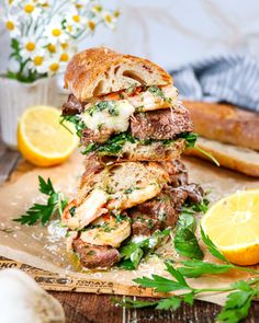 a stack of grilled sandwiches on top of a cutting board next to sliced lemons