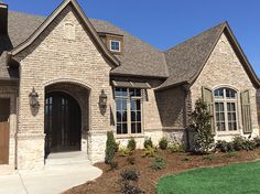 a large brick house with lots of windows and landscaping around the front door is shown