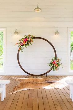 a large wooden circle with flowers on it in the middle of a room filled with white benches