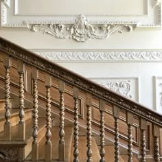 an ornate wooden staircase with white walls and wood handrails