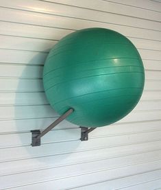 a large green ball mounted to the side of a white garage wall next to a metal bar