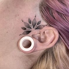 a woman's behind the ear has a flower tattoo on it