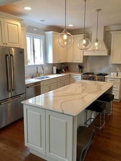 a kitchen with white cabinets and marble counter tops