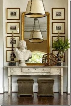 a white table topped with a large mirror and a lamp next to a busturine