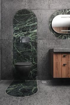 a bathroom with marble walls and flooring next to a sink, toilet and mirror