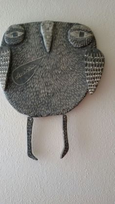 a metal bird hanging from the side of a wall