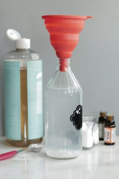 a glass bottle with an orange top sitting on a counter next to other bottles