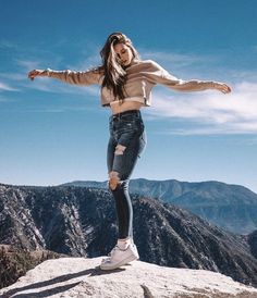 a woman standing on top of a mountain with her arms outstretched