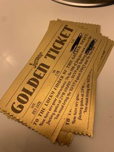 three tickets sitting on top of a white counter next to a light fixture with the word gold ticket written on it