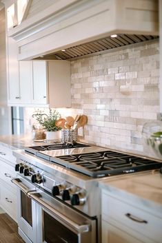 a stove top oven sitting inside of a kitchen next to a counter with wooden utensils