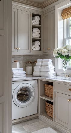 a washer and dryer in a bathroom with lots of towels on the shelves