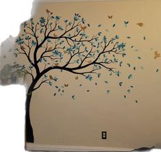 a tree with blue leaves and birds painted on the wall next to a potted plant