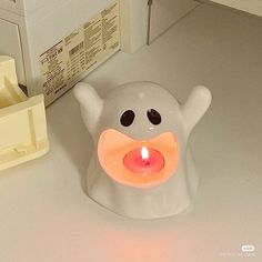 a white candle holder with an orange light in the shape of a ghost