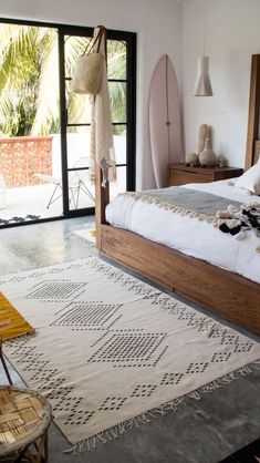 a bedroom with a bed, rug and two surfboards on the wall behind it