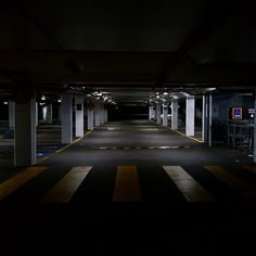 an empty parking garage with yellow and black stripes on the floor, at night time