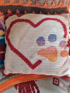 a close up of a pillow on a bed with a heart and ducky face