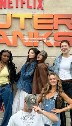 a group of young people standing next to each other in front of a sign that says outer banks