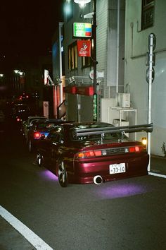 a car parked on the side of the road at night with its hood up and lights on