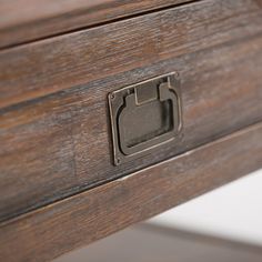 a close up of a drawer on a wooden table with metal handles and knobs