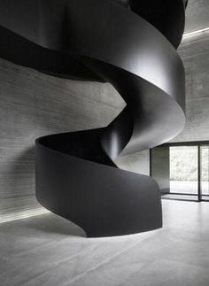 a black spiral staircase in an empty room