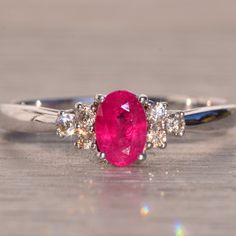 an oval ruby and diamond ring on a wooden surface