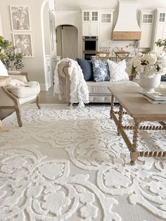 a living room filled with lots of furniture and white rugs on top of a wooden floor