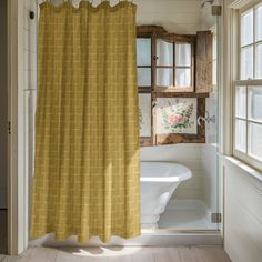 a yellow shower curtain hanging in front of a window next to a white bath tub