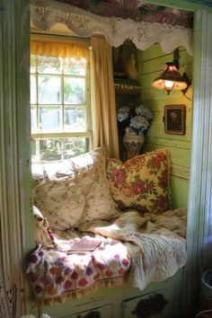 a window seat in the corner of a room with pillows and blankets on top of it