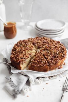 a cake is cut into pieces and sitting on a table with plates, forks and silverware