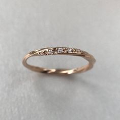 a gold wedding band with five diamonds on the top and bottom, sitting on a white surface