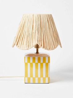 a lamp with a yellow and white checkered shade on the base, sitting on a white surface