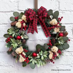 a christmas wreath on a brick wall with red berries, pine cones and teddy bears