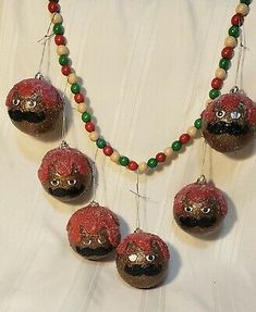 an assortment of red and green ornaments hanging from a white curtain with beads on it