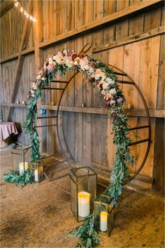 a wedding arch decorated with flowers and greenery on the floor in front of a wooden wall