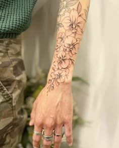 a woman's arm with flowers on it and two rings in front of her