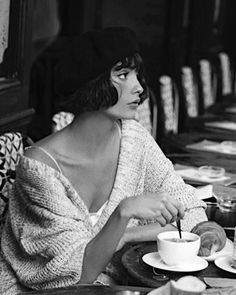 a woman sitting at a table with a cup and saucer in front of her