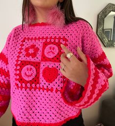 The newest addition to the Lucy Collection - a handmade to order crochet jumper! This pink crochet jumper has been lovingly handmade with a 'mixed emotions' design at the front, featuring happy and sad faces, a love heart and a flower, with checkered details - each design will be slightly different and unique. The sleeves are striped pink and red, and extra-long for that cosy oversized jumper feeling. A bright pink and red jumper for anyone that loves colour and wearing slow fashion.