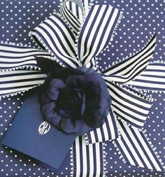 a blue and white polka dot wrapping paper with a flower on the top, tied to it