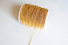 a spool of gold colored thread on a white surface with a chain attached to it