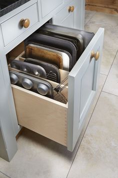 an open drawer in the middle of a kitchen with pots and pans on it