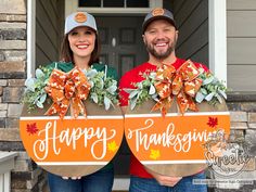 two people standing in front of a house holding thanksgiving decorations